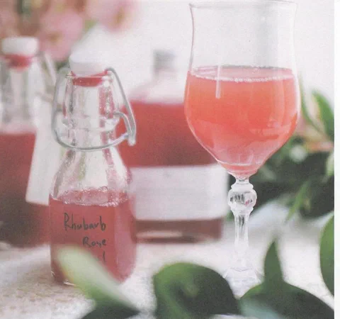 Jarabe de fresa y flor de jamaica, embotellado, junto a una copa servida con agua con gas