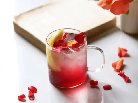 Jarabe de rosas casero servido en una taza, con pétalos y limón