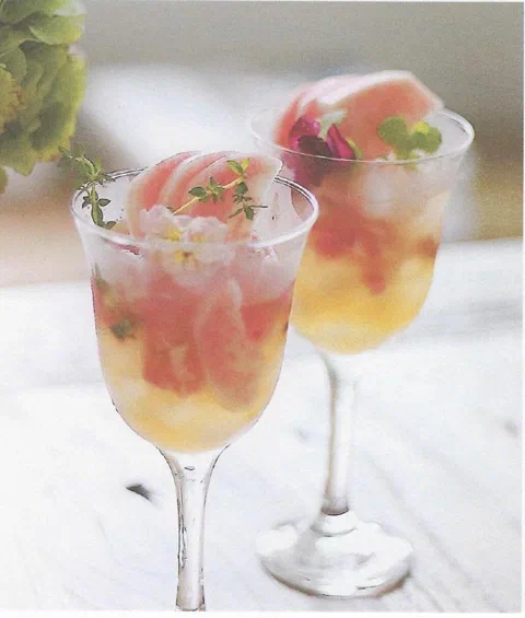 Ade de durazno, con rodajas de durazno, hierbas y flores comestibles