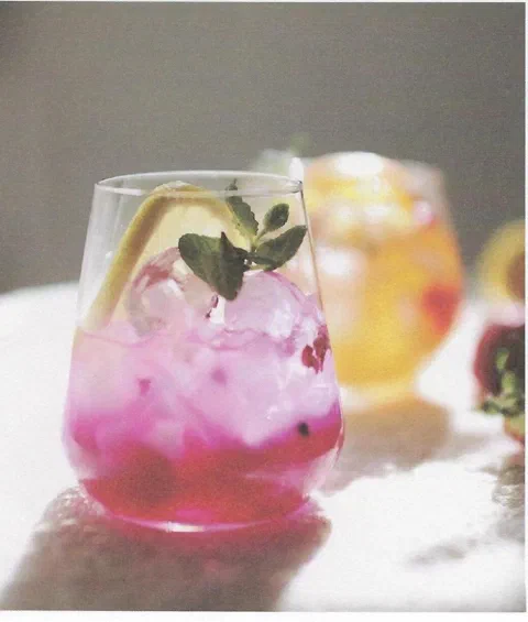 Ade de limón rosa, de un color rosa-morado intenso, con rodaja de limón y menta