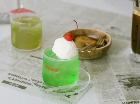 Melón soda, en un vaso verde con helado y cereza encima