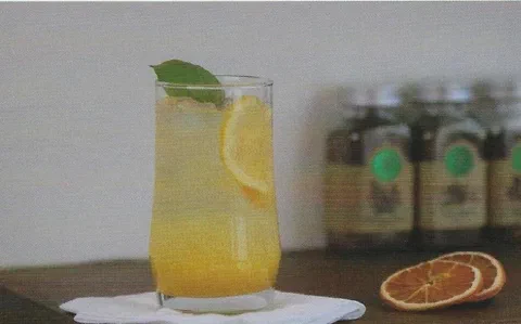 Ade de naranja y limón, con rodaja de limón y hierbas de decoración