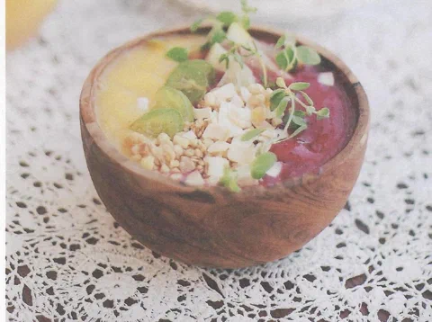 Smoothie de mango y pitahaya, en capas amarilla y roja, con fruta fresca encima