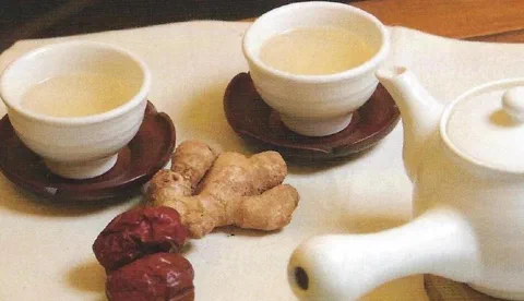 Té de dátil chino, jengibre y pera, servido en dos tazas junto a una tetera blanca