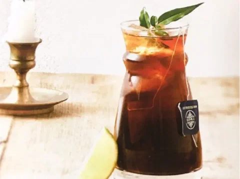 Café frío con té earl grey, con la bolsita de té y una rama de hierba