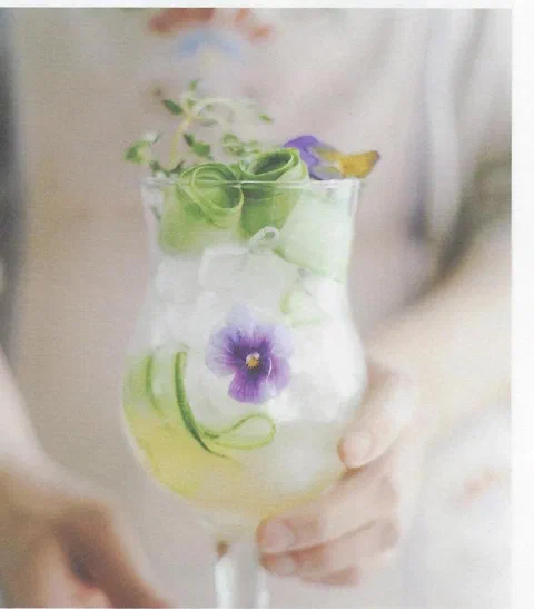 Cóctel de limón y pepino, con cintas de pepino y flores comestibles