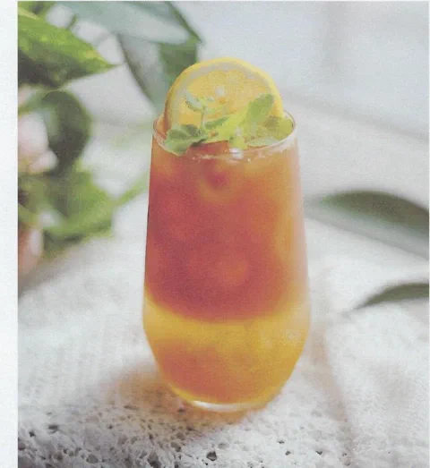 Highball de toronja, miel y earl grey, con rodaja de limón y hierbas de decoración