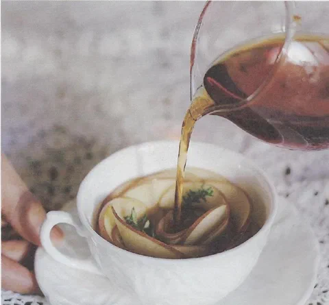 Manzana y canela con té negro, con rodajas de manzana armadas en forma de rosa dentro de la taza