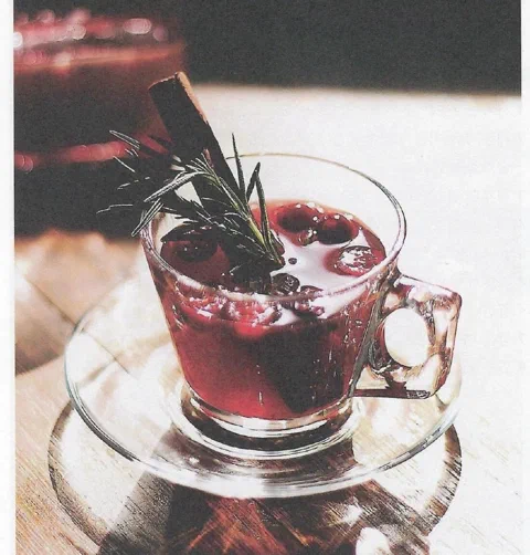 Vino caliente especiado en té, con rama de canela y romero de decoración