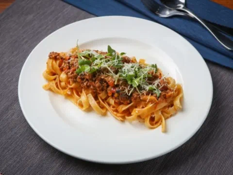Tagliatelle al ragù, con parmesano y hojas frescas encima