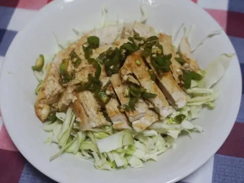 Pechuga de pollo yurinchi en tiras sobre lechuga, bañada en salsa de cebolla china y ajo