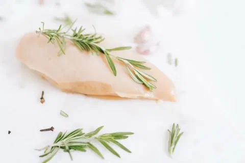 Pechuga de pollo cruda con romero fresco