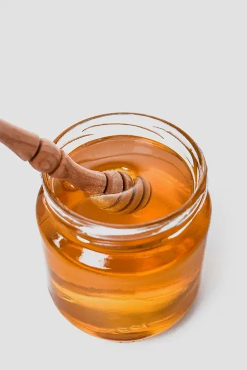 Miel en un frasco de vidrio con un aplicador de madera