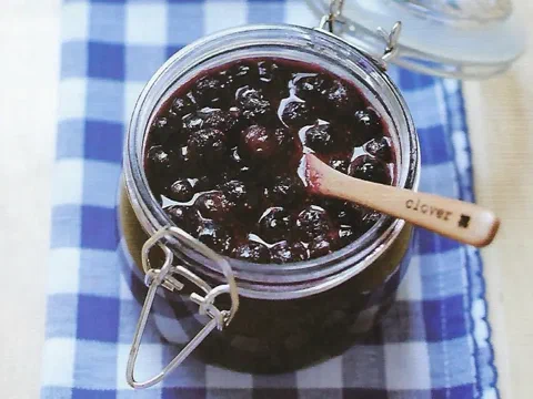 Frasco de compota de arándanos con una cuchara de madera