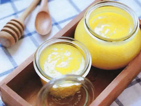Frascos de lemon curd, con un cucharón de miel al costado