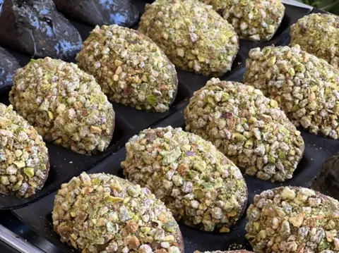 Madeleines cubiertas de pistacho picado, con el centro relleno de ganache
