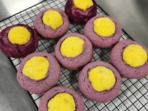 Galleta de camote morado partida, mostrando el centro de queso crema y trozos de camote asado