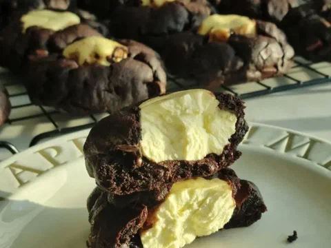 Galleta triple chocolate partida, mostrando el centro de queso crema entre los tres chocolates