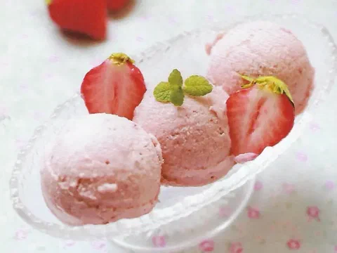 Bolas de helado de fresa en una copa, decoradas con fresas y menta