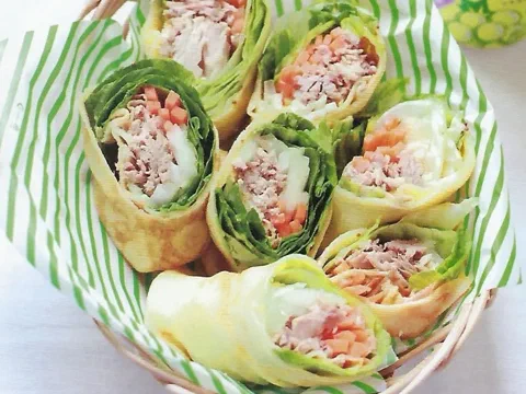 Crepes enrollados como wrap, cortados por la mitad mostrando el relleno de atún, zanahoria y lechuga