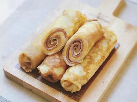Crepes enrollados con espiral de jamón y queso visible en el centro