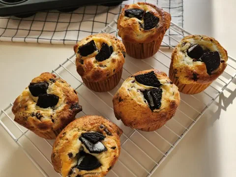 Muffins partidos mostrando el relleno de queso crema y Oreo, con trozos de galleta visibles