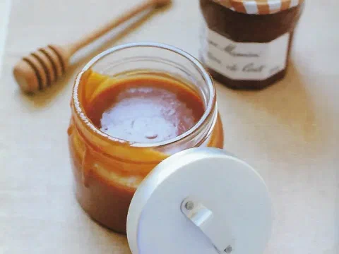 Frasco de salsa de caramelo con un cucharón de miel al costado