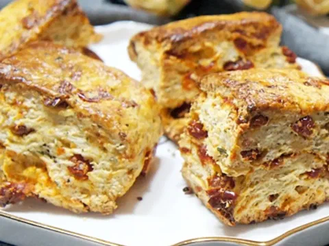 Scones de tomate, albahaca y queso partidos, mostrando el tomate y el queso derretido adentro