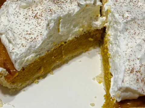 Pay de zapallo cortado, mostrando el relleno horneado bajo la crema de queso batida