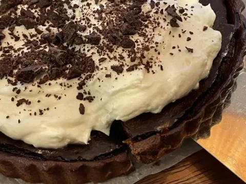 Tarta de chocolate y queso crema, cubierta de crema batida y chocolate rallado