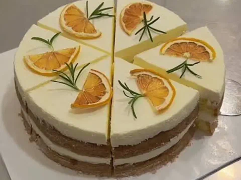 Cheesecake de limón cortado en porciones, decorado con rodajas de cítrico deshidratado y tomillo
