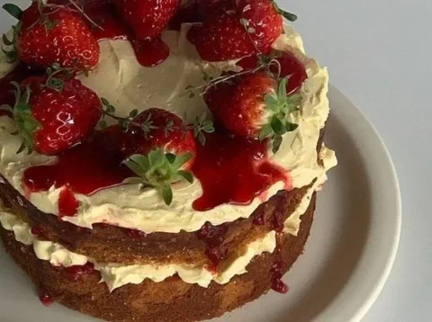 Torta de frambuesa sin cubrir del todo, decorada con fresas y hierbas frescas