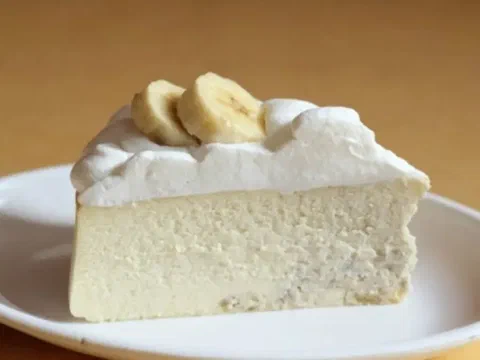 Rebanada de torta de plátano y queso crema, con láminas de plátano fresco encima
