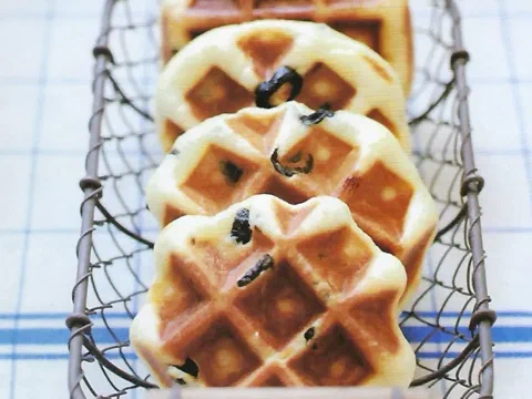 Waffles de Lieja con aceituna negra apilados en un canasto de metal