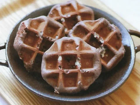 Waffles de Lieja oscuros de arroz negro, con azúcar perlada visible, en una sartén de hierro