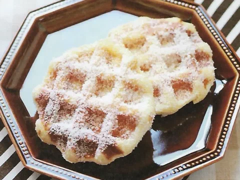 Waffles de coco cubiertos de coco rallado sobre un plato oscuro