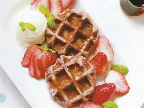 Dos waffles de Lieja de fresa servidos con helado de vainilla, fresas frescas y sirope