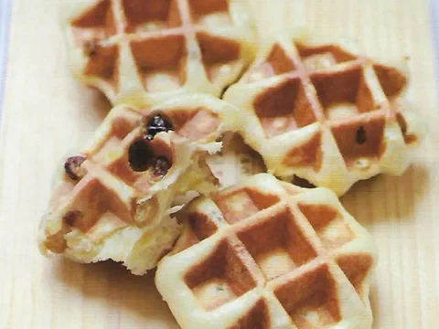 Waffles de Lieja con pasas sultanas visibles, apilados sobre una tabla de madera