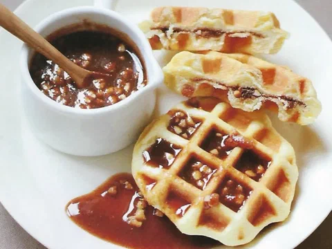 Hotteok waffles partidos, con el relleno de azúcar rubia y frutos secos derretido, junto a un bowl de sirope