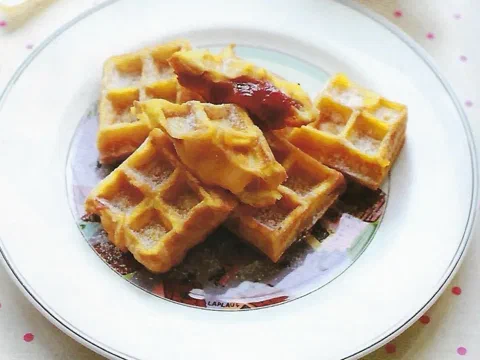 Cuadrados de tostada francesa con sello de waffle, uno de ellos relleno de mermelada de fresa
